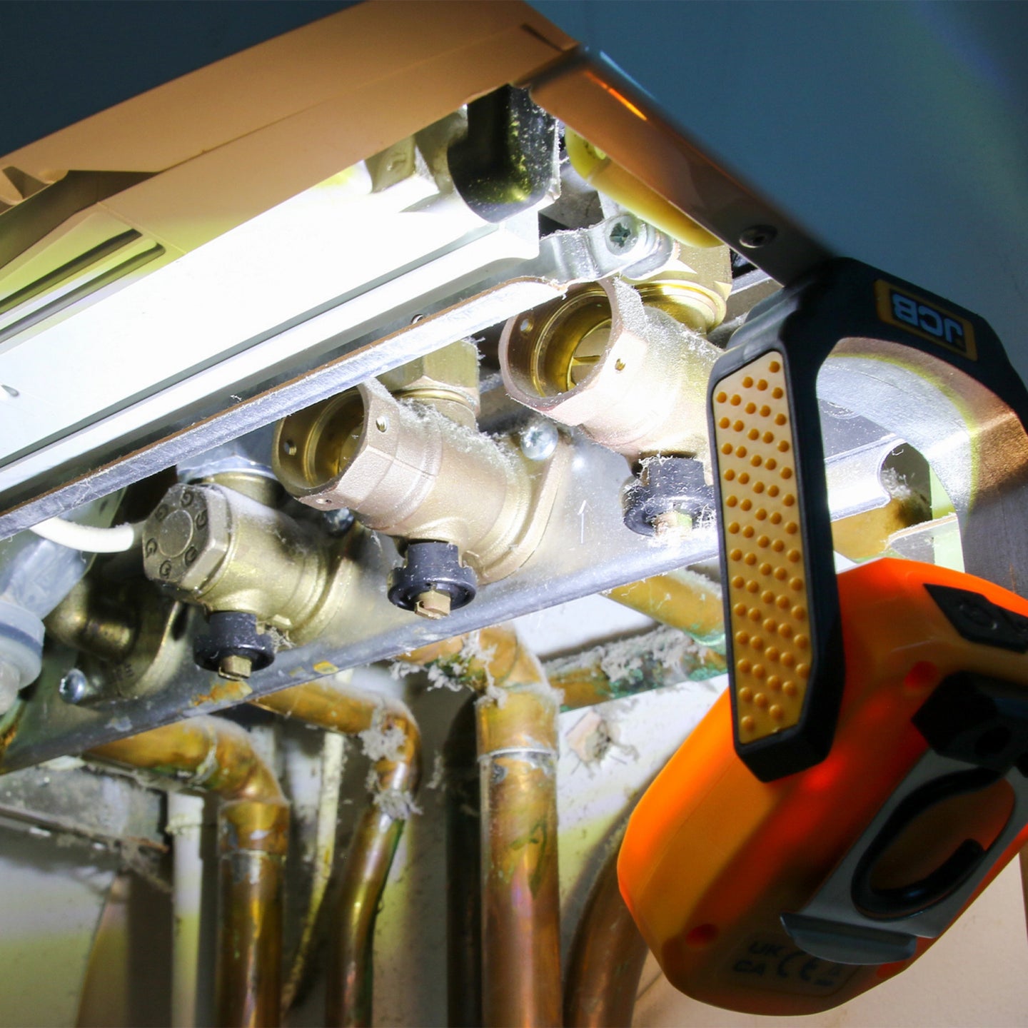 Lampa robocza JCB zawieszona przy instalacji z miedzianymi rurami