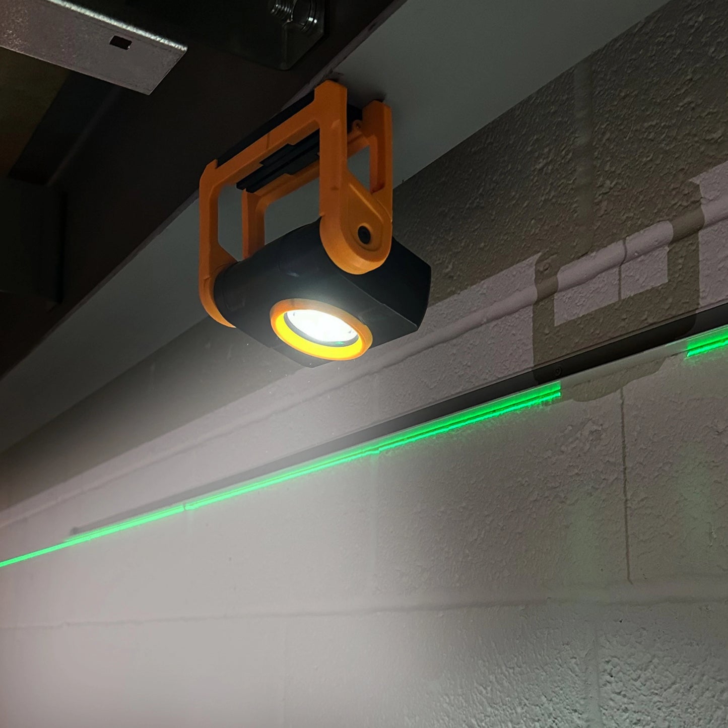 Lampa robocza JCB zawieszona pod belką, oświetlająca ścianę roboczą
