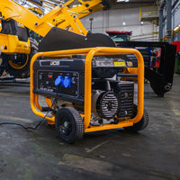 Mały agregat prądotwórczy JCB GPL3610P 3,6 kW podłączony w hali serwisowej na tle maszyn budowlanych JCB