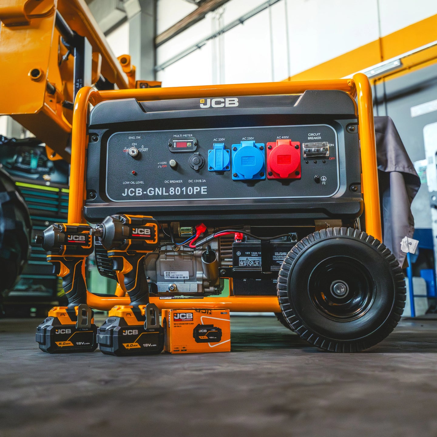 Agregat prądotwórczy JCB GPL8010PE w warsztacie z elektronarzędziami JCB wiertarko-wkrętarką udarową i akumulatorami 18V 5Ah obok agregatu
