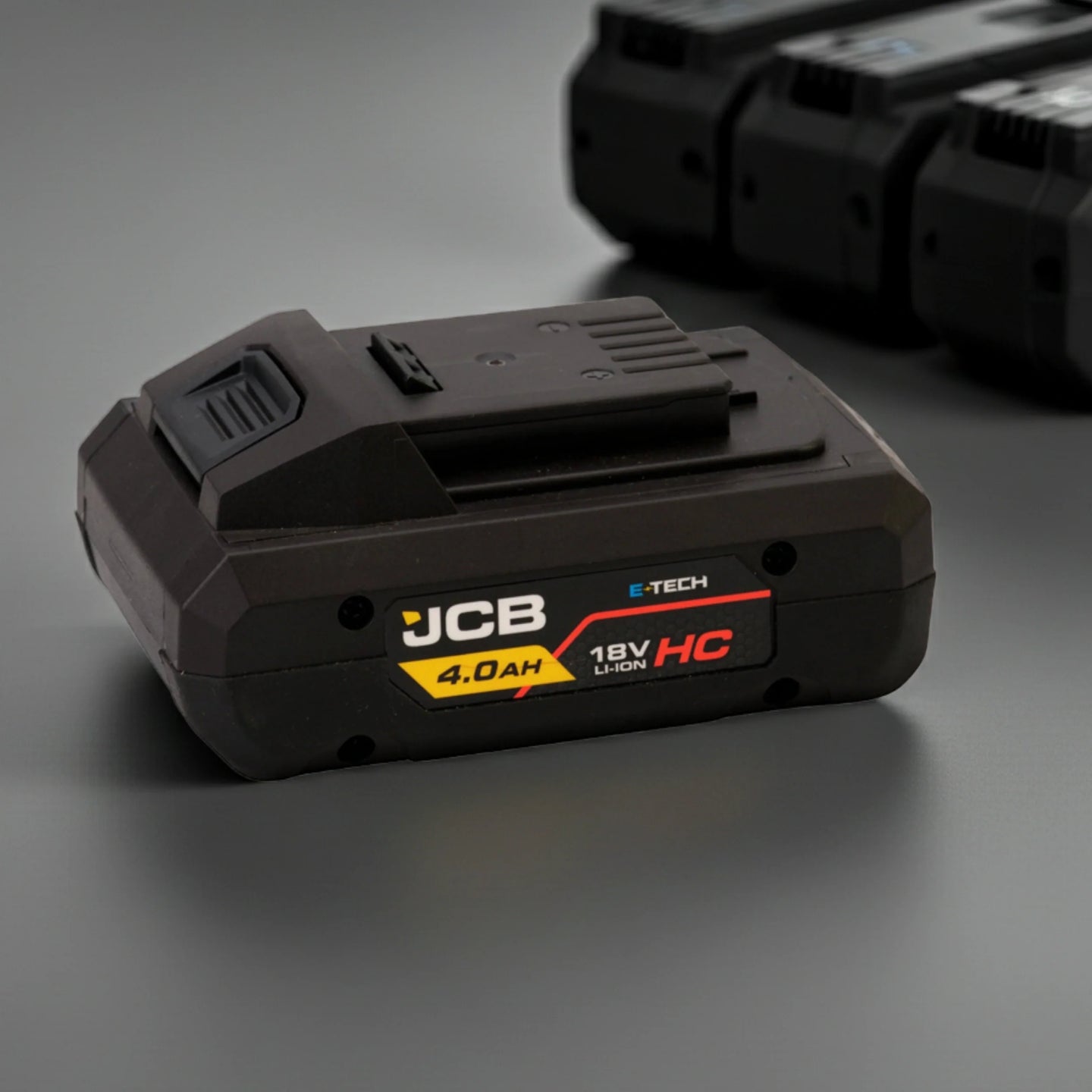 akumulator li-ion JCB E-Tech 18V HC 4.0Ah na drewnianym blacie obok wkrętarki i gwoździ z tekstem wysoka pojemność