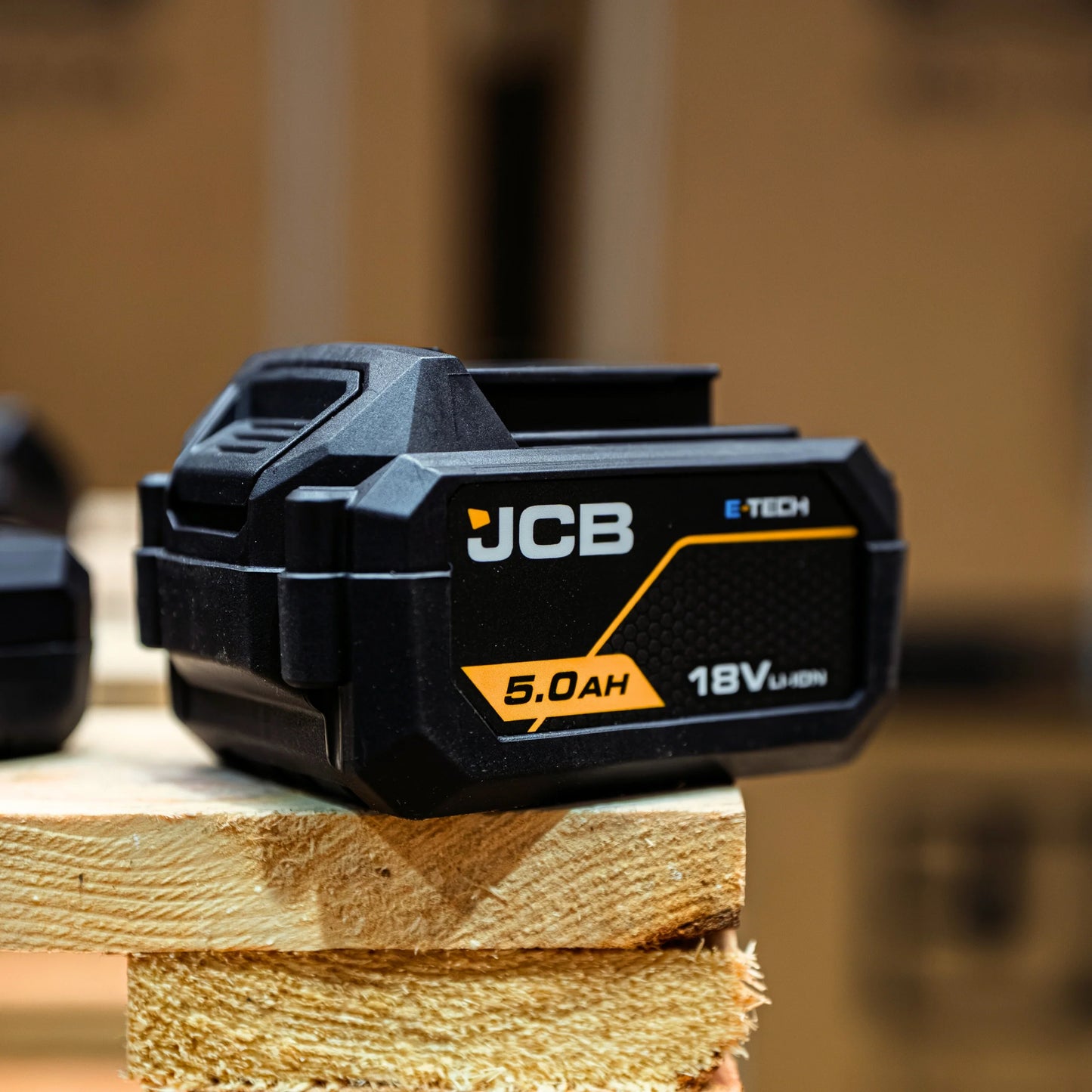 akumulator li-ion JCB E-Tech 18V 5.0Ah na desce w warsztacie ujęcie z góry z tekstem inteligentna komunikacja cyfrowa