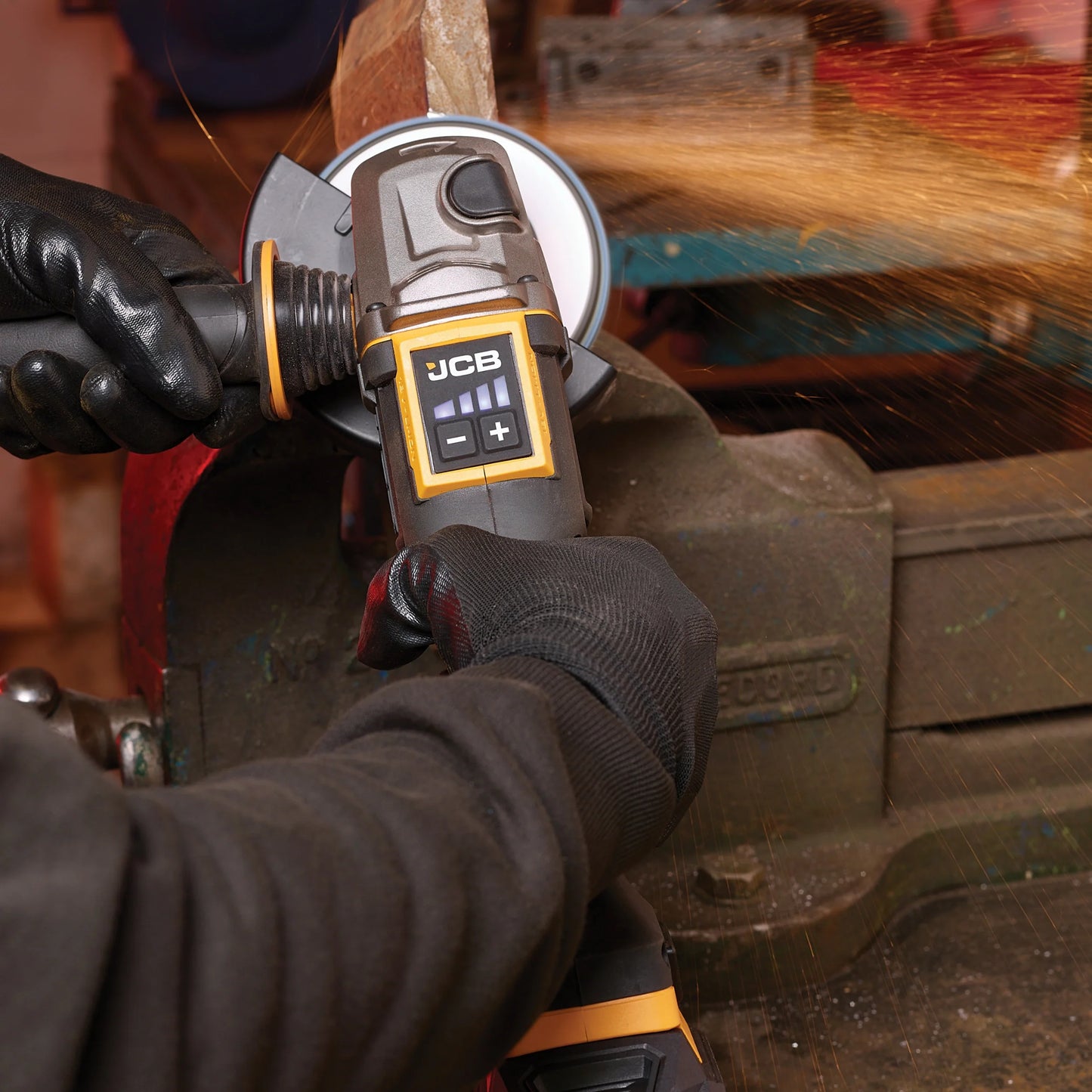 szlifierka kątowa JCB Professional 18V podczas szlifowania metalu z iskrami w rękach operatora w rękawicach z tekstem 9000 obr./min