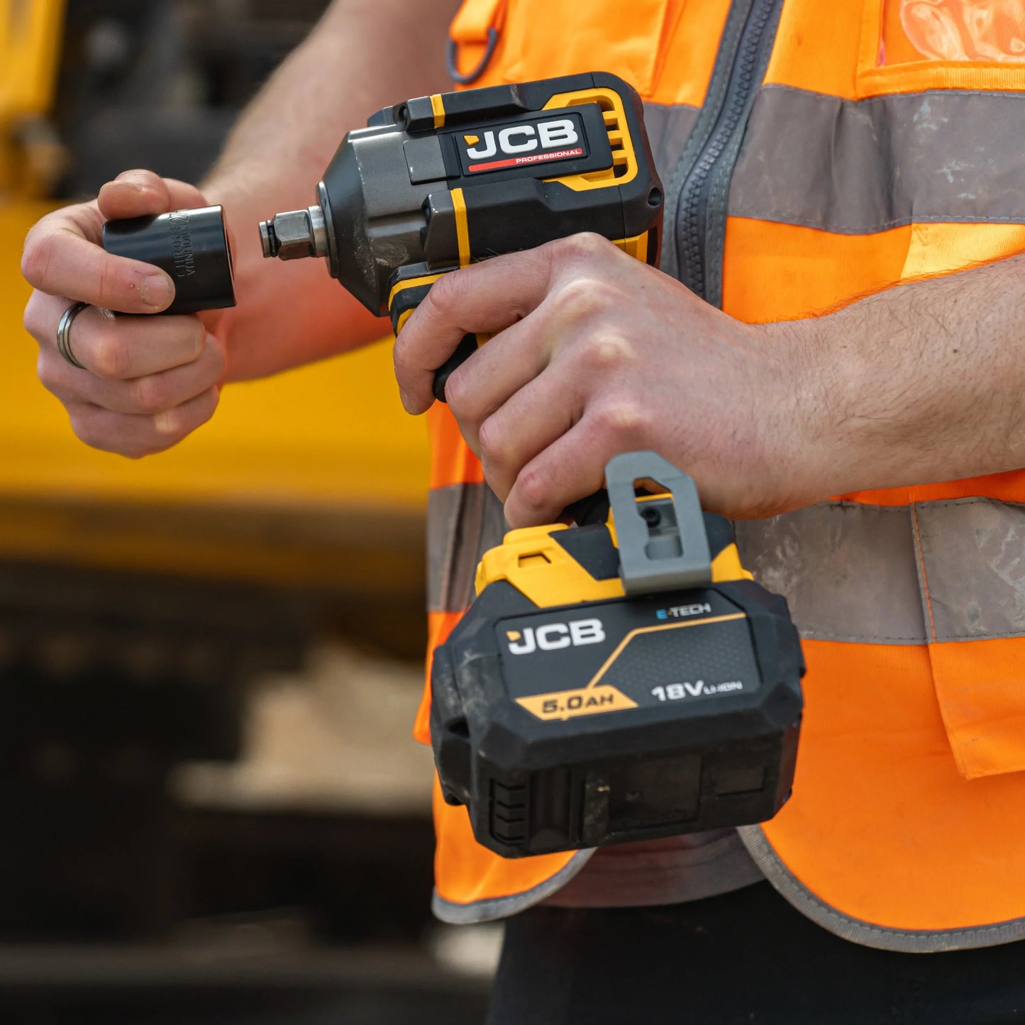 klucz udarowy akumulatorowy JCB Professional 18V 5.0Ah w rękach pracownika w kamizelce z tekstem uchwyt 1/2 Square Drive