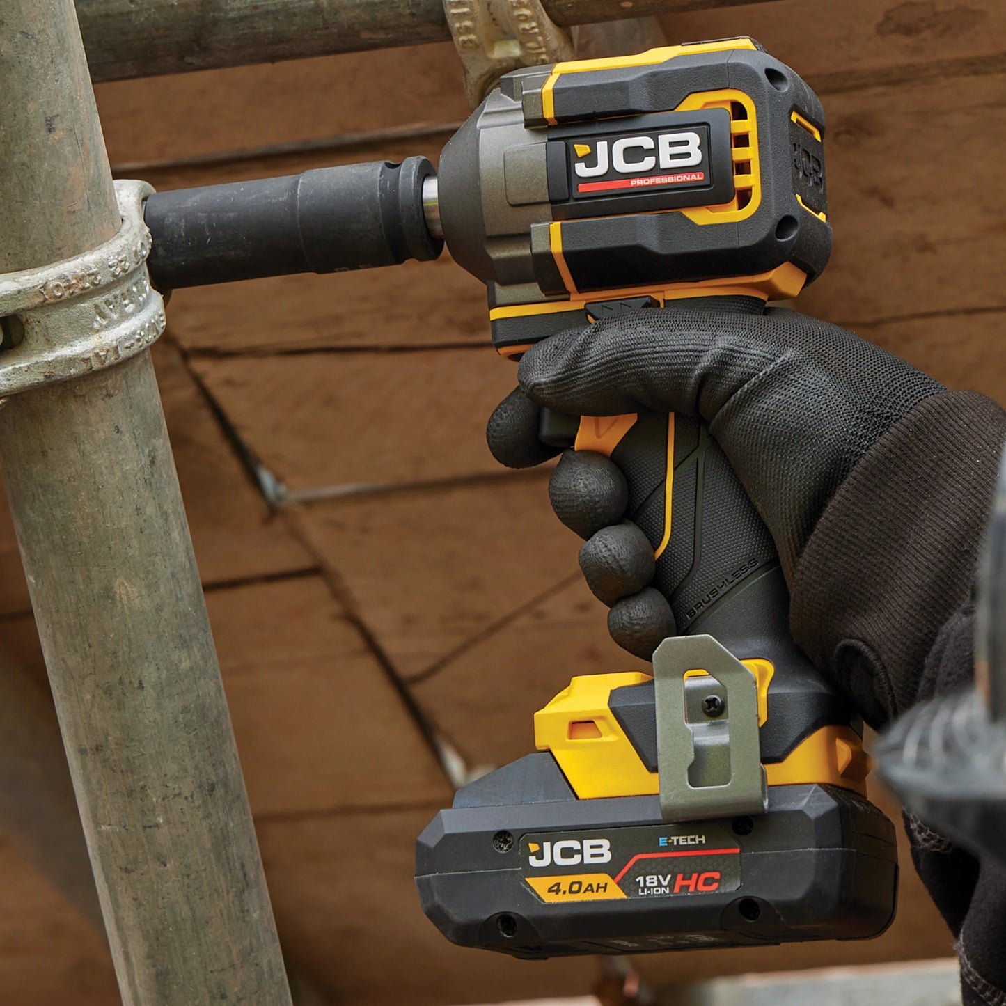 klucz udarowy JCB Professional 18V podczas dokręcania złącza rury w rękach operatora w rękawicy z tekstem Uchwyt 1/2 Square Drive