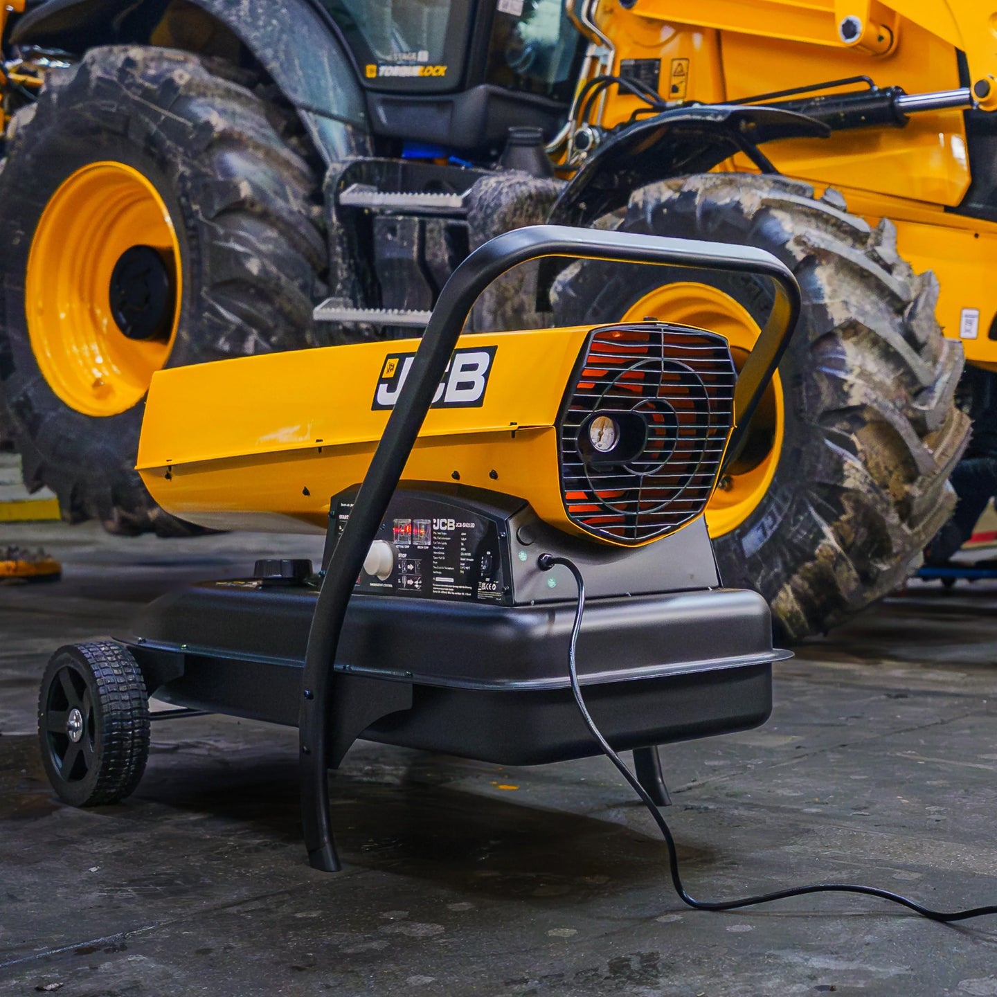 Nagrzewnica JCB SH215DP24 podczas pracy, widok z tyłu z wentylatorem, w tle maszyna JCB, tekst: Najwyższa moc grzewcza 63 kW