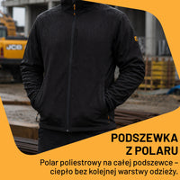 Mężczyzna w czarnej kurtce roboczej softshell JCB na placu budowy, tekst Podszewka z polaru