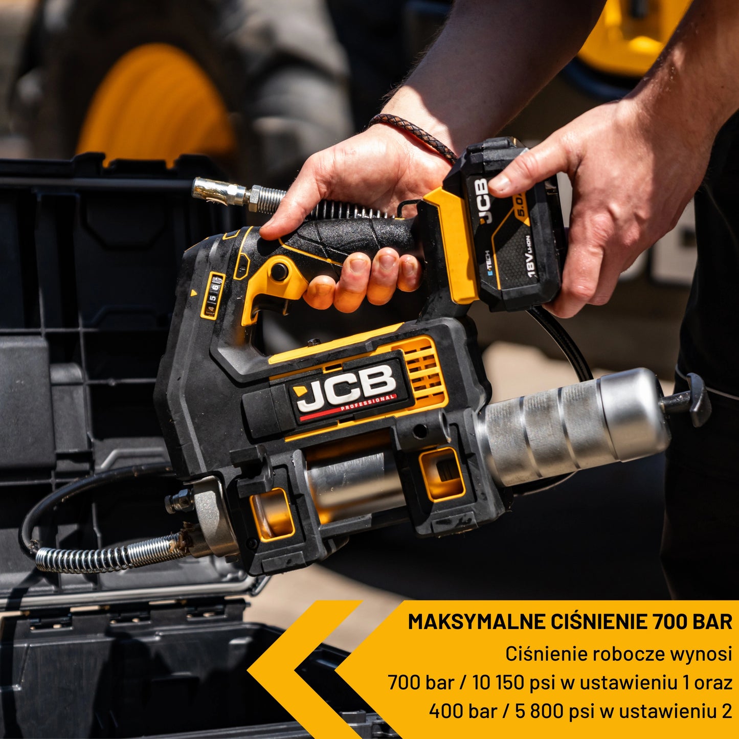 Smarownica akumulatorowa JCB 18PGG-zestaw-1 trzymana w dłoni nad skrzynią narzędziową maksymalne ciśnienie 700 bar